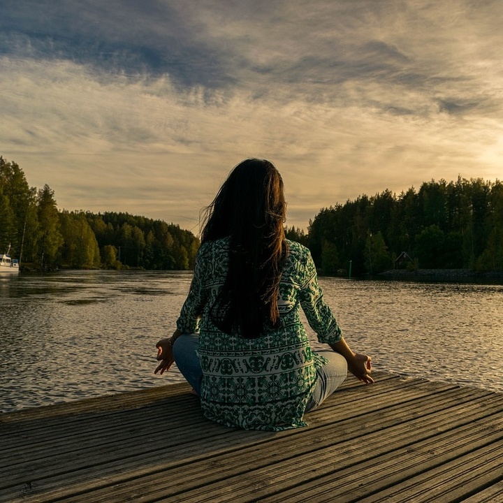 Frau meditiert am See